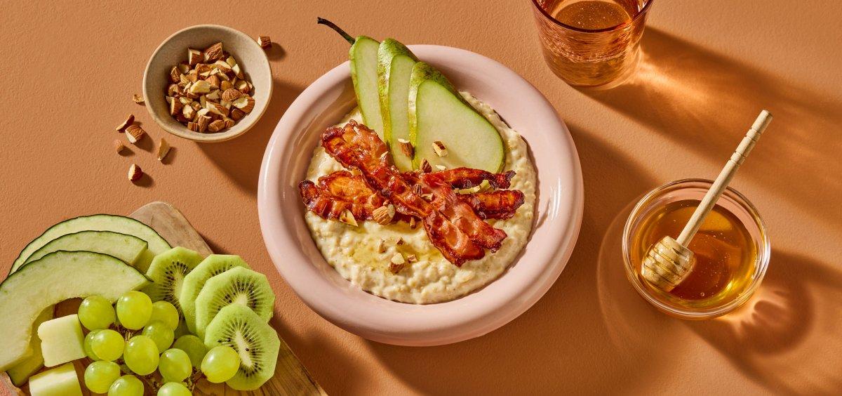 Havregrøt med sprøstekt bacon, pære, ristede mandler og honning.